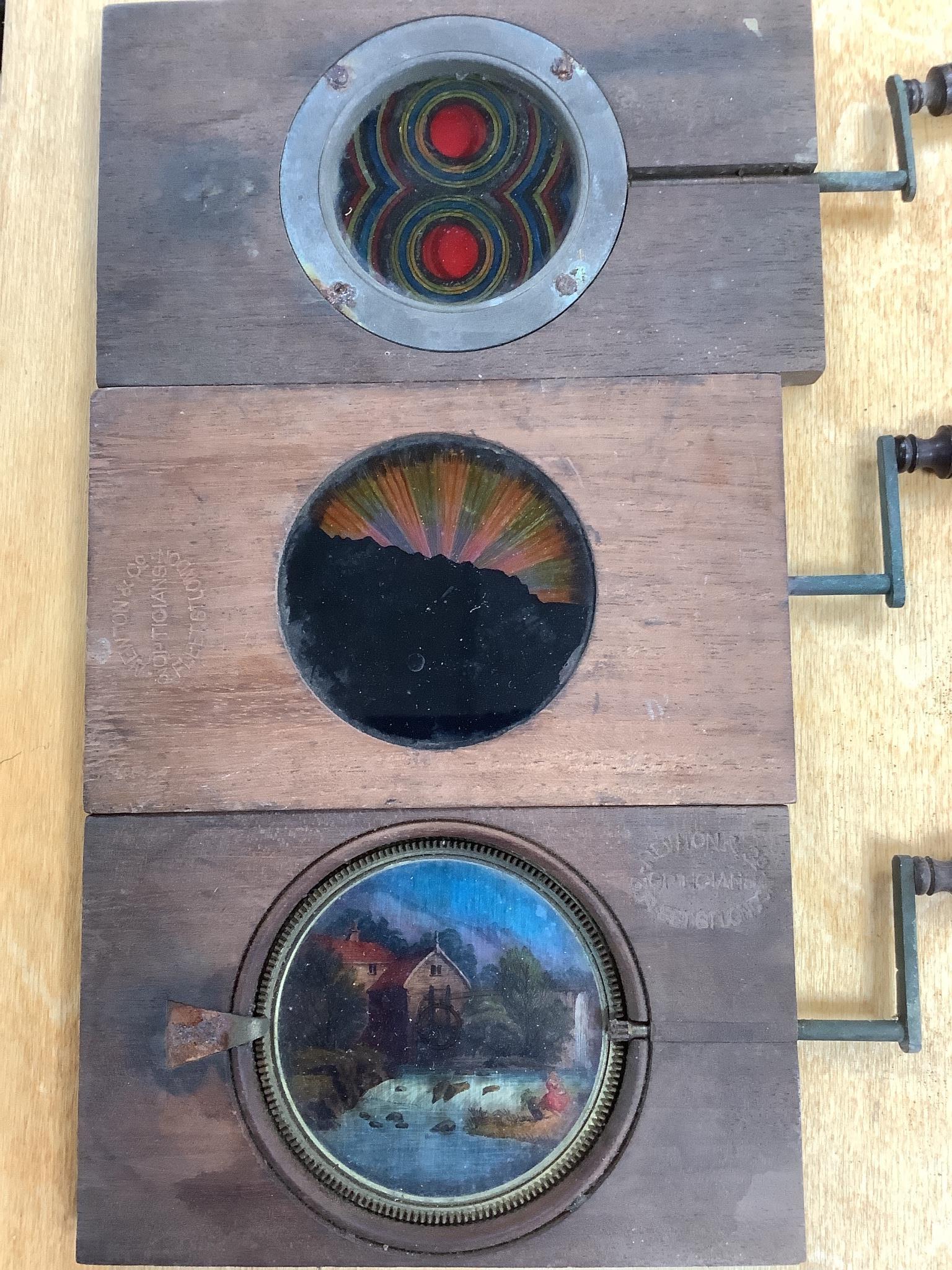 Three Victorian mechanical mahogany and glass lantern slides and a collection 19th/20th century glass lantern slides